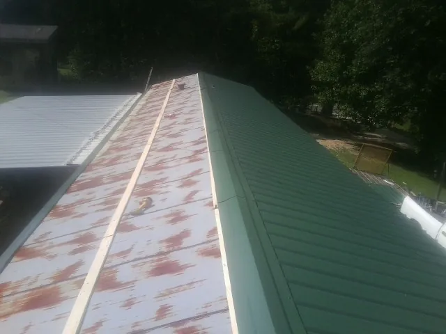 Old rusted panels beside newly installed green metal roofing — Wind Damage Roof Repair by Roofing Brothers in Johnson City