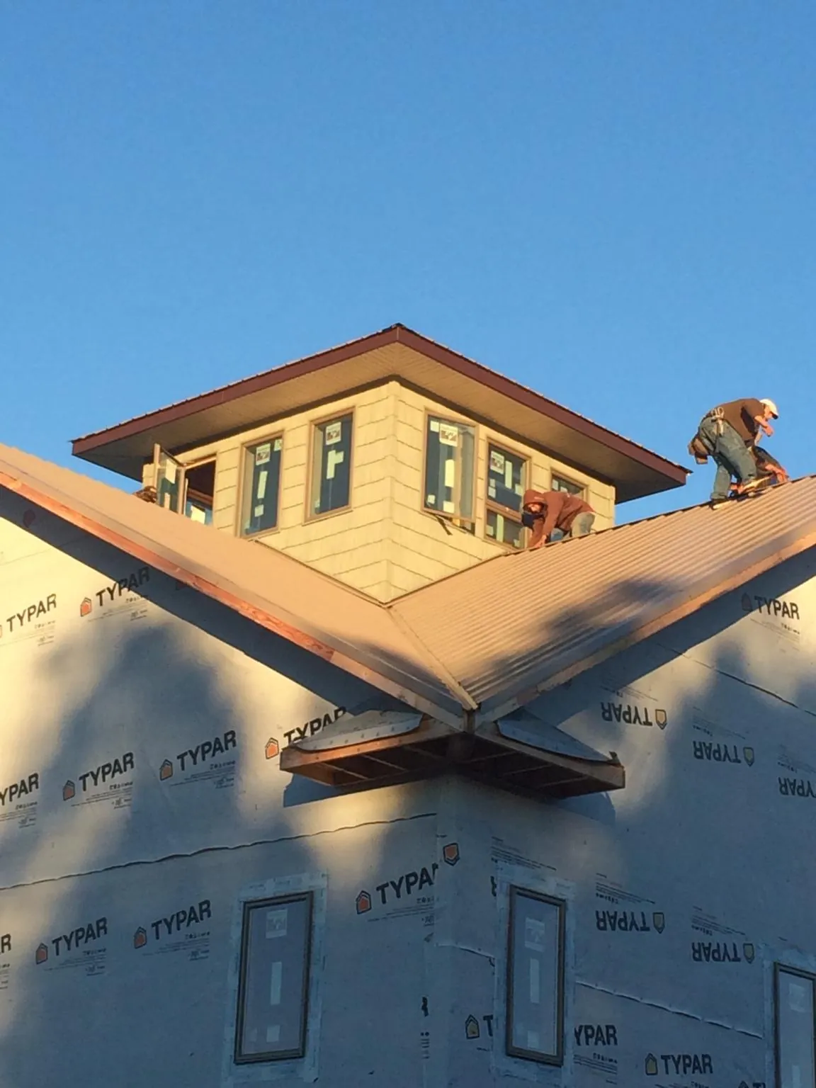 Roofers working around a rooftop cupola on a new metal roof at sunset — Roof Waterproofing in Johnson City by Roofing Brothers